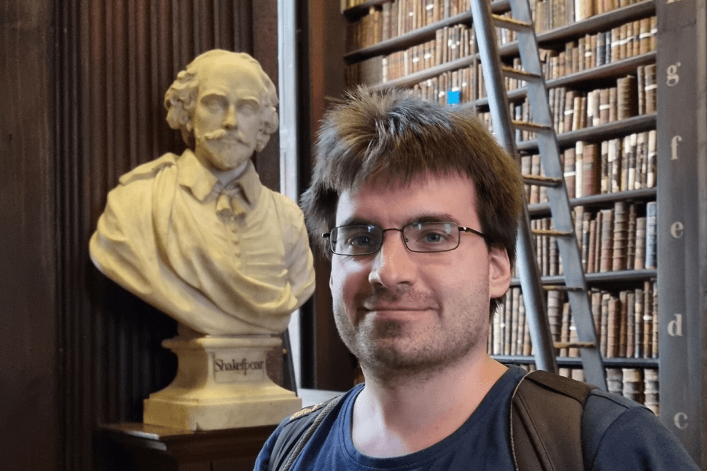 Portraitfoto von Maximilian Runge-Segelhorst, vor einem großen Bücherregal und mit einer alten Büste im Hintergrund